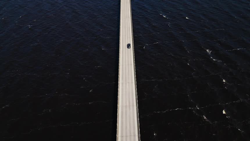 A car drives down a bridge over water