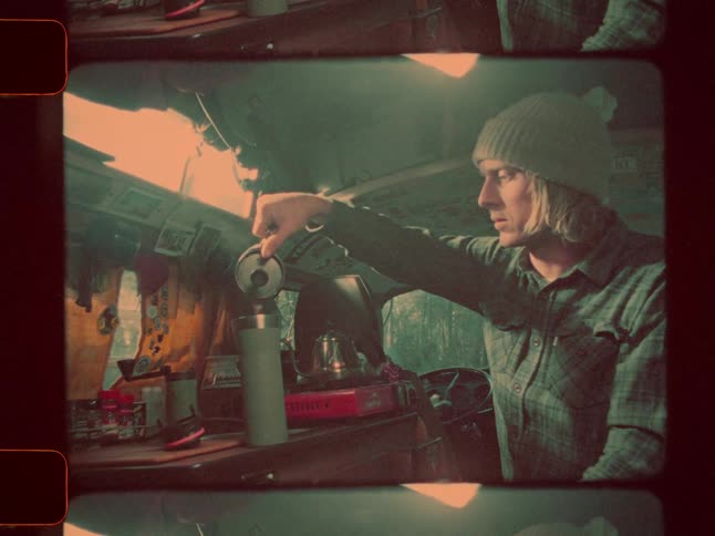 Blonde man sitting in the back of a van pours from a small kettle into a thermos