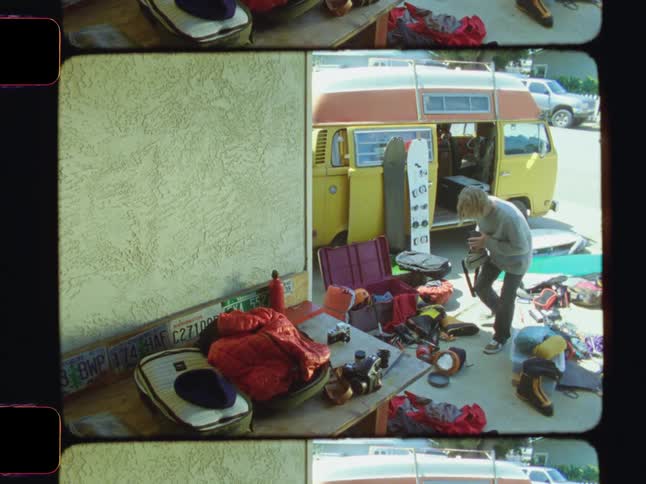 A person arranging scattered luggage around a parked yellow van