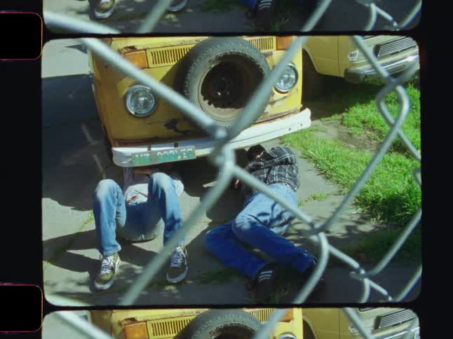 Two men are laying under the van repairing it