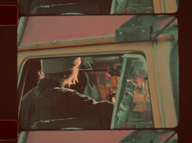A man inside his van pours a kettle of hot water
