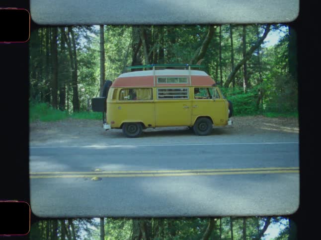 A footage of a bus parked at the road side beside the woods