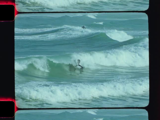 A person in a wetsuit rides an ocean wave captured on vintage film