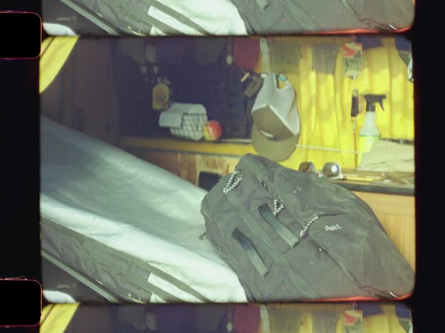 The interior of a van features wooden panels luggage scattered about and yellow curtains hanging by the windows