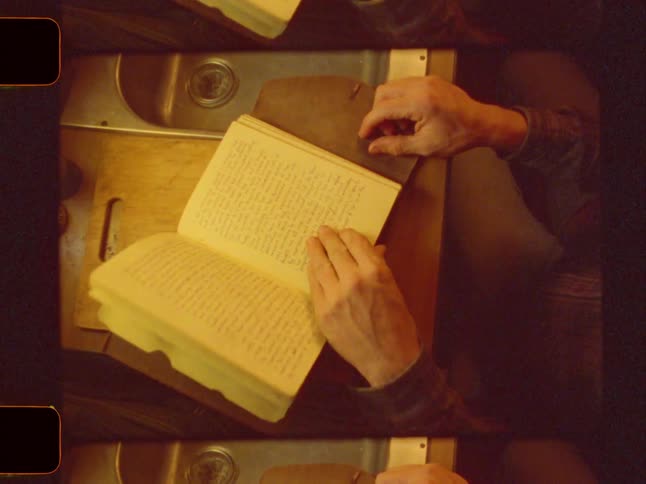 A hand flips through the pages of an open notebook uncovering photo slides tucked within