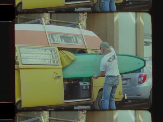 Man pulling a surfboard out of a van