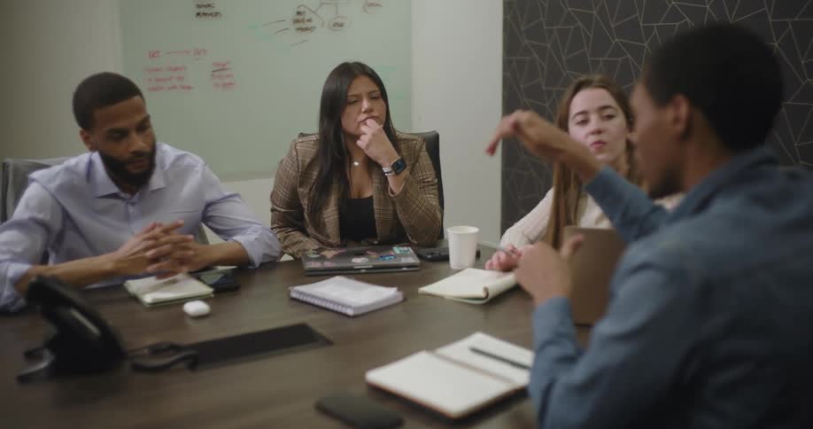Four coworkers in a conference room having a discussion during a meeting