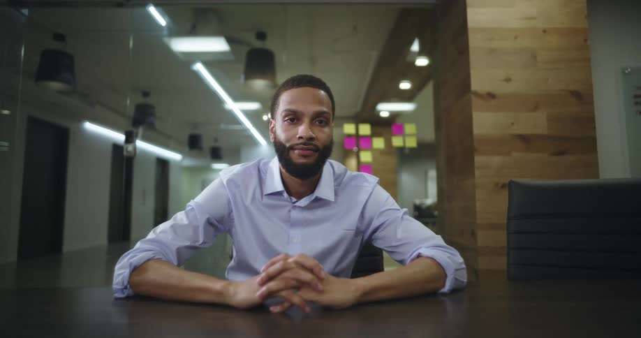 A bearded man sitting at a conference table in a contemplative mood