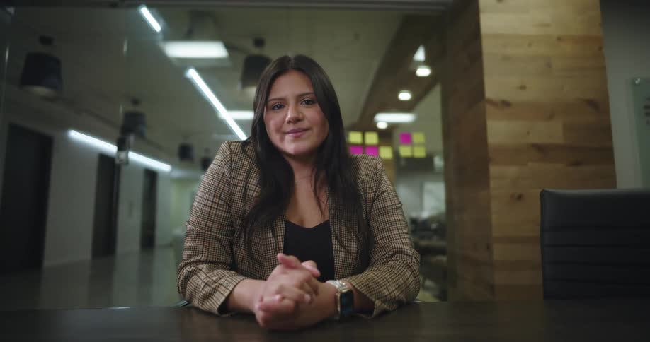 A woman smiles while and clasps her hands
