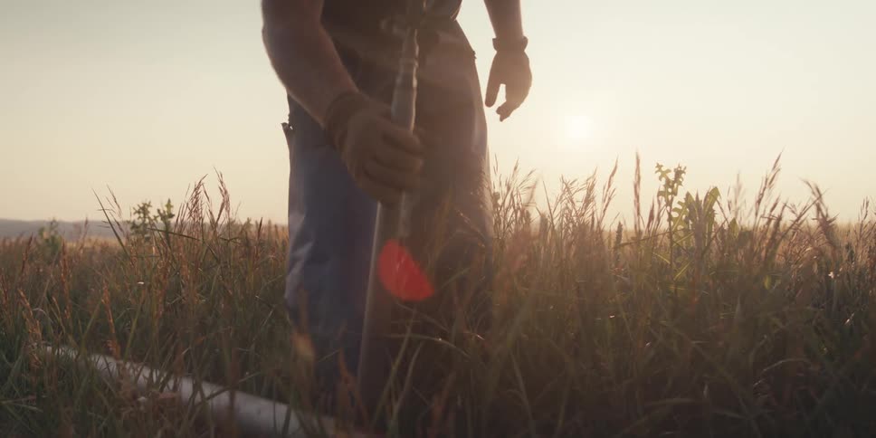 A farm worker attaches a pipe on the field