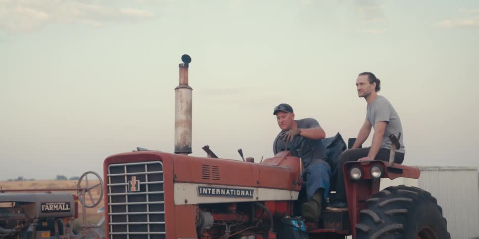 Two men are on a tractor on a farm