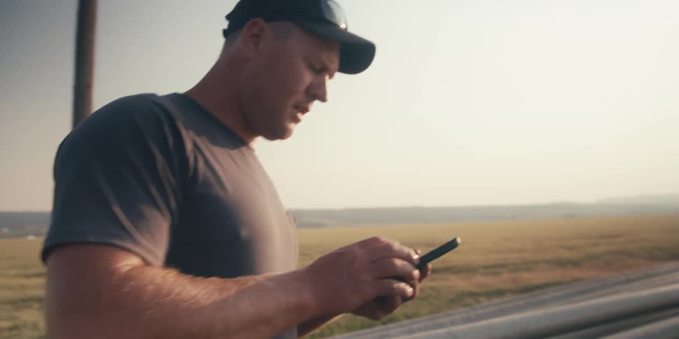 Man checking cell phone on the edge of a wheat field
