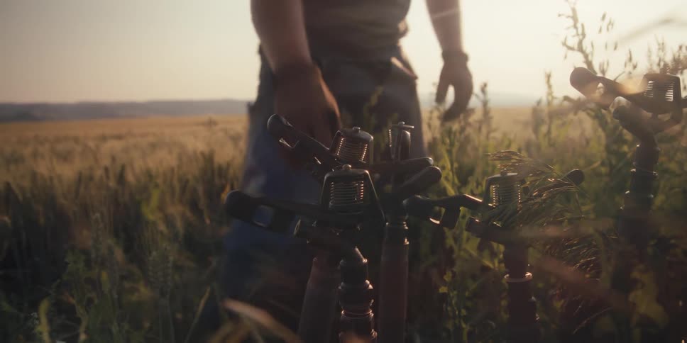 Man picking up a sprinkler pipe in the middle of a field