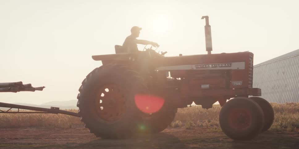 A farmer gets on a tractor and starts to move it