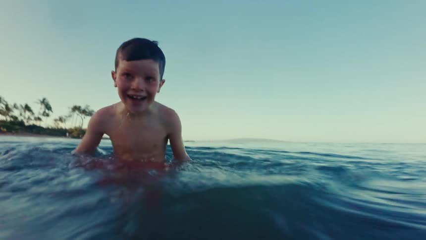 A boy joyfully runs toward the waves on a bluewater beach during a stunning sunset