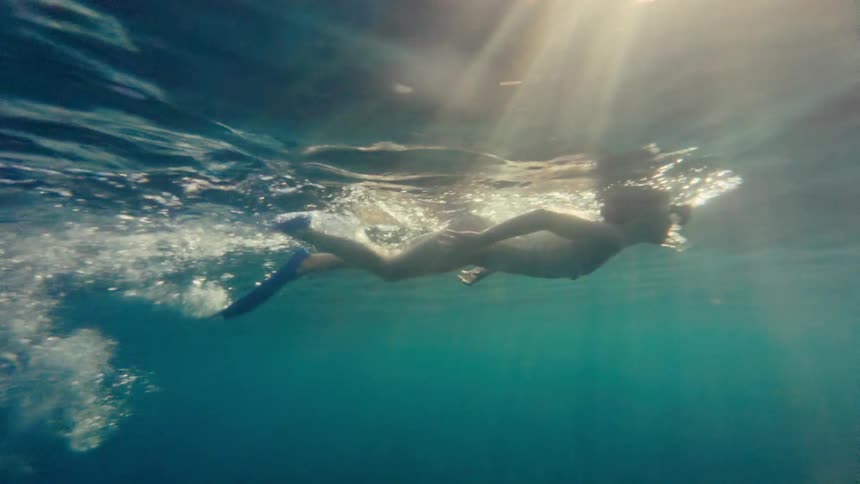An underwater shot of a child swimming in deep water