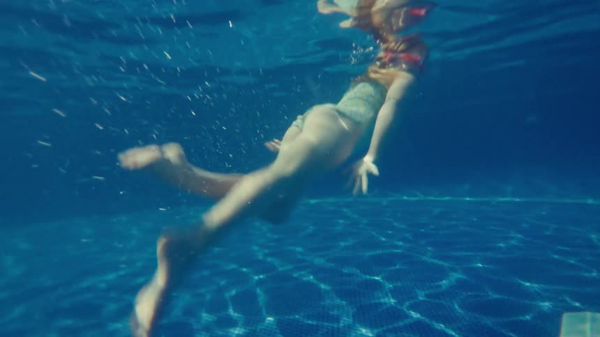 A girl is swimming underwater in a pool
