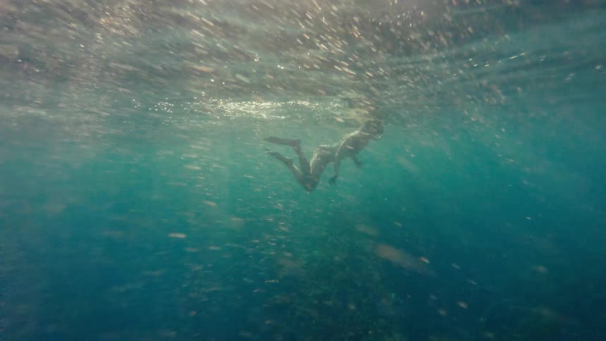 Woman snorkels near the surface while bubbles fill the water