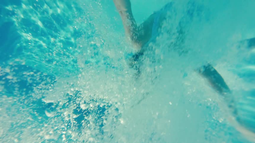 A girl jumps into a pool with a big splash