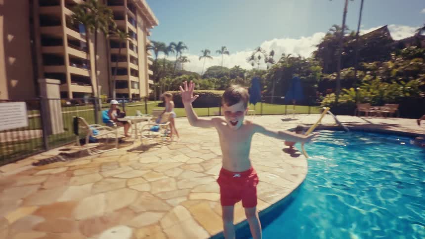 A child jumps in the pool water by the hotel