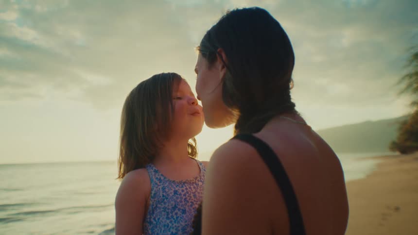 Mother and daughter rub noses on the beach