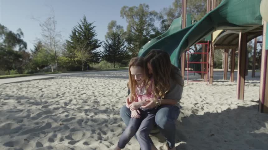 A woman and girl go down a slide