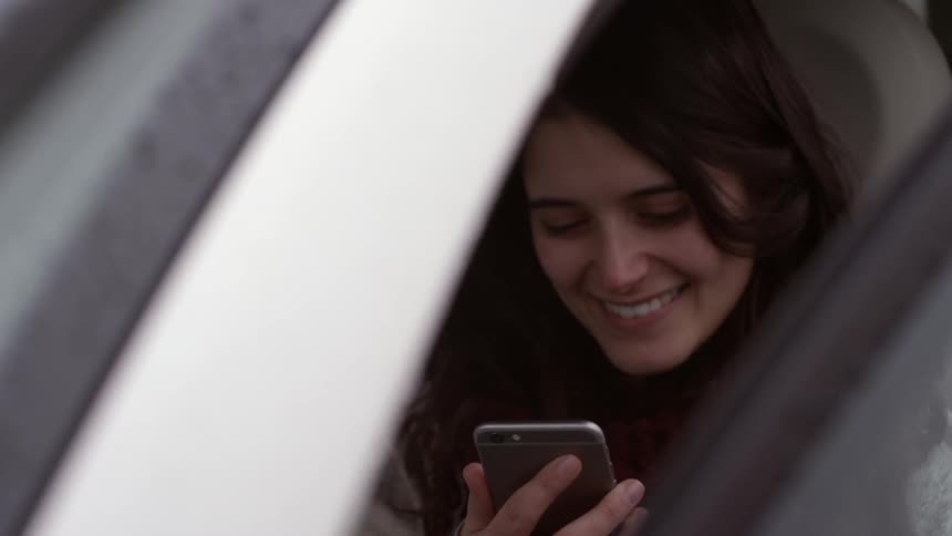 A woman laughs while looking at her phone
