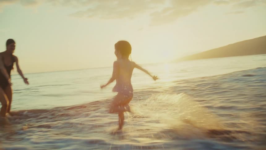 A daughter runs up to her mom on the beach