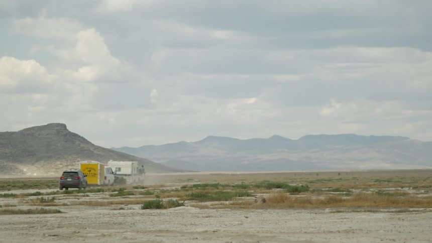 Vehicles are moving across the desert in the distance