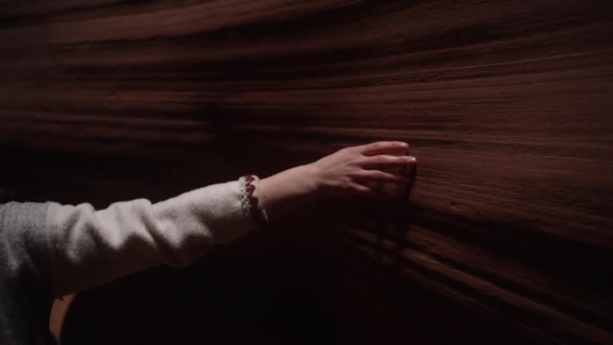 A woman is tracing her hands across the bedrock of this cavern
