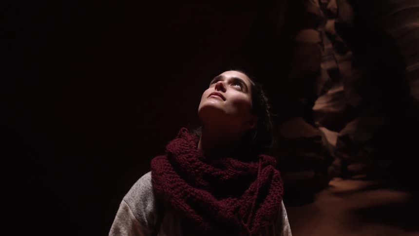A woman looks up in a dark cavern