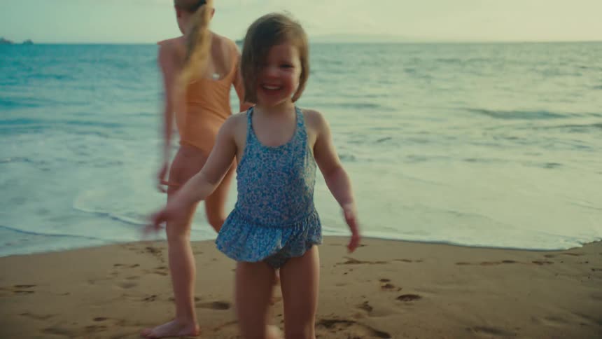 Two young girls running and playing together near the water on the beach