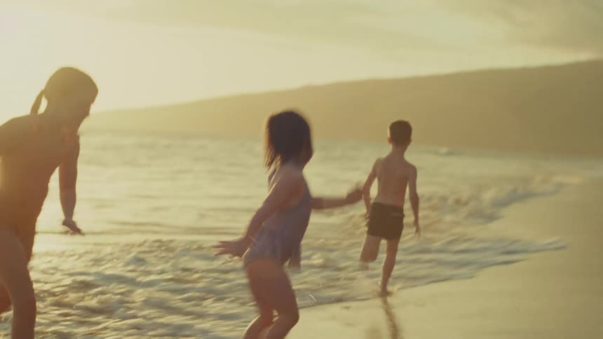 Children playing in the sea with their mother