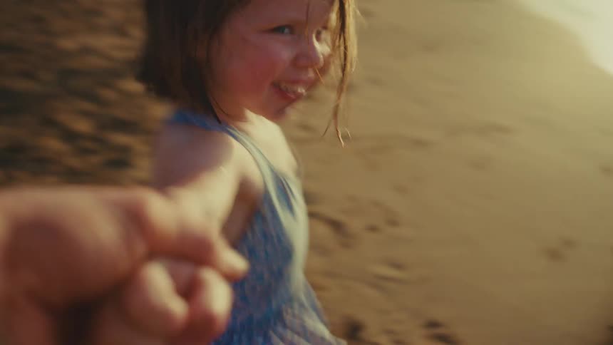 A child is happy while being led around the sand on the beach