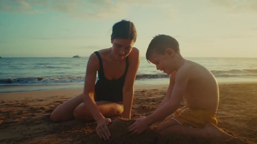 A mother and her son play in the sand on a beach