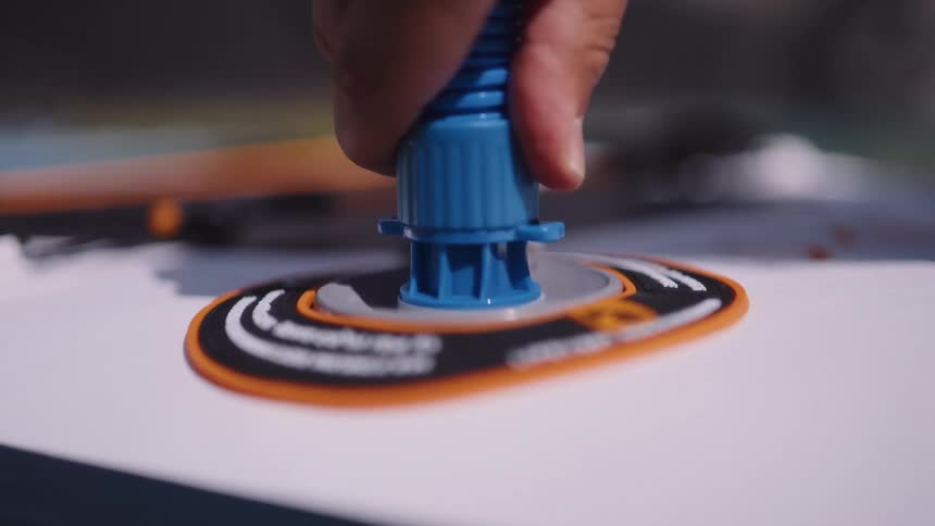 A closeup shows a hand in the process of disconnecting an air pump from the valve of an inflatable raft
