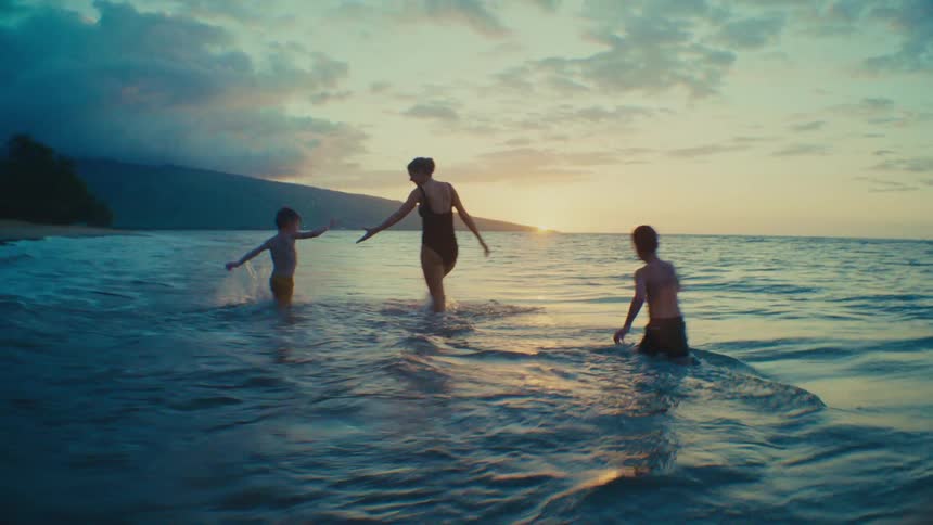 A Joyful Family Running Together at the Beach at Sunset