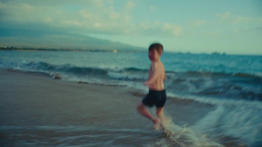 A boy runs in the water along the beach