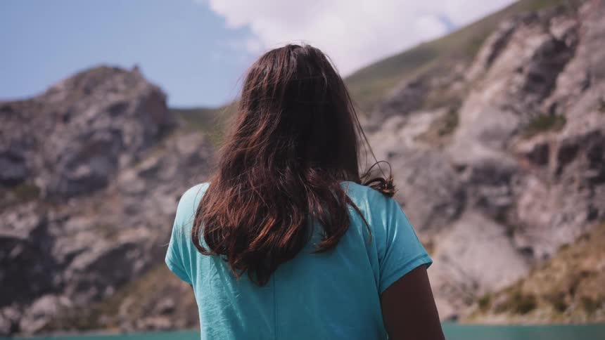 The woman is paddling towards the rock face cliff