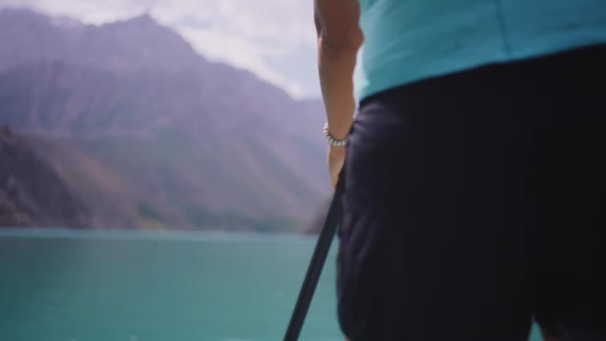 Extreme back close up of woman paddling with an oar on a lake