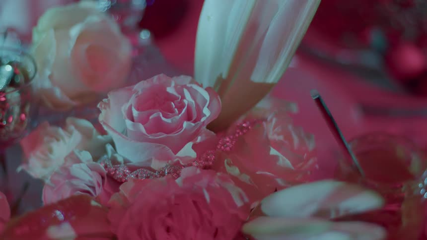 A closeup captures a softly lit floral arrangement predominantly featuring roses with light radiating across the scene