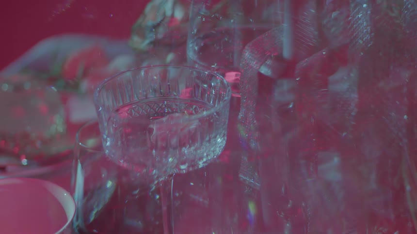 An array of glassware filled with liquid under a pink lighting scheme creating a blurry ethereal effect