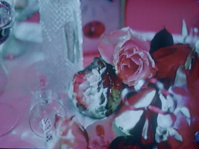 Shadows flow over flowers and glassware including the stemware holding dice