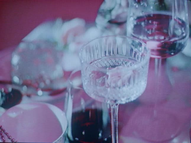 Shadows pass over glassware and a cup with a strand of jewelry