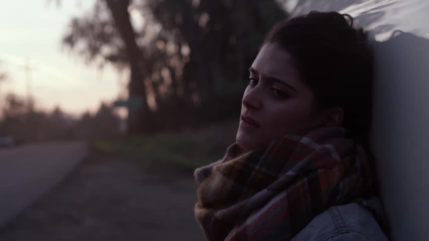A woman sits on the roadside waiting for something