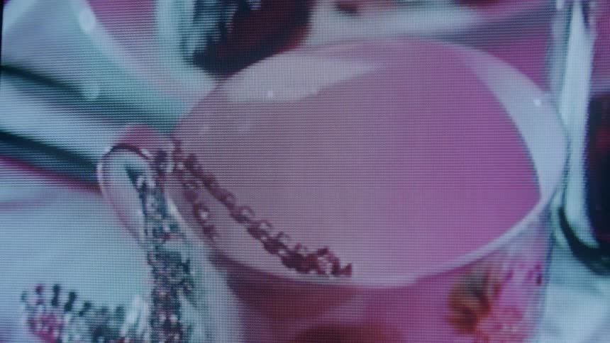 Shadows flow across a pink cup and the necklace hanging on it