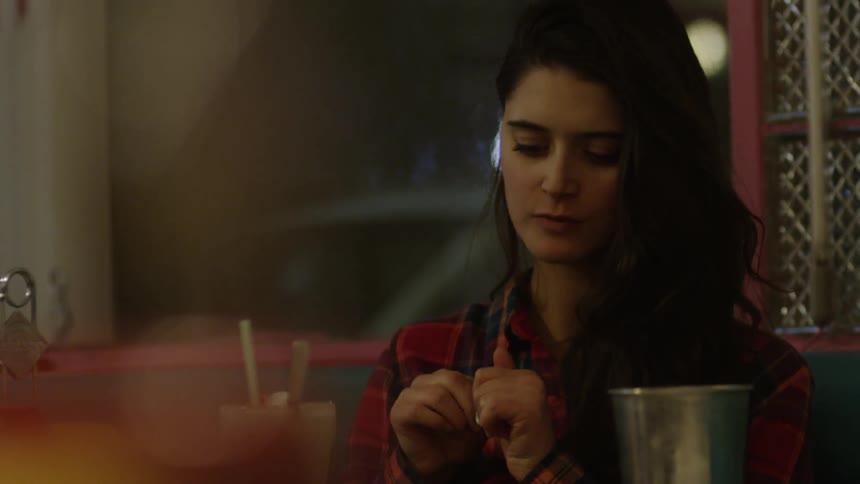 A woman is eating at a restaurant table at night