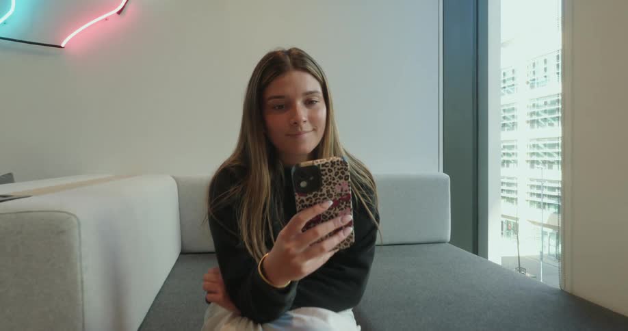 A woman is sitting and using her cell phone