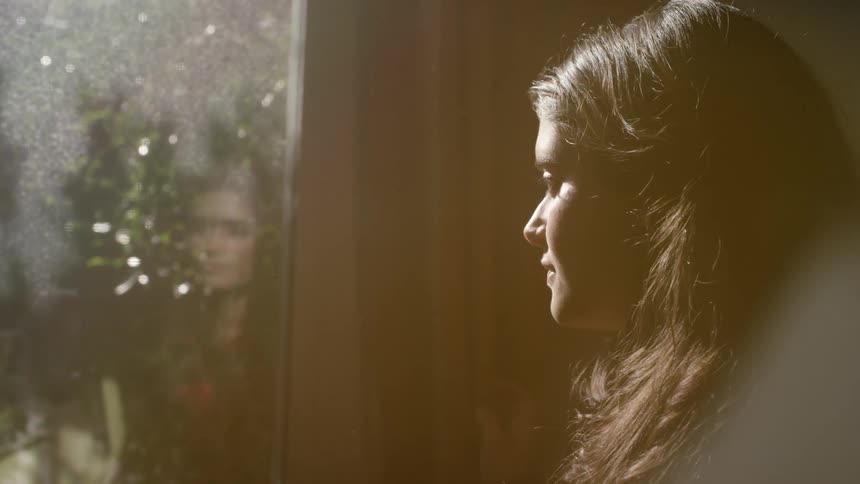 A woman looks out an old window
