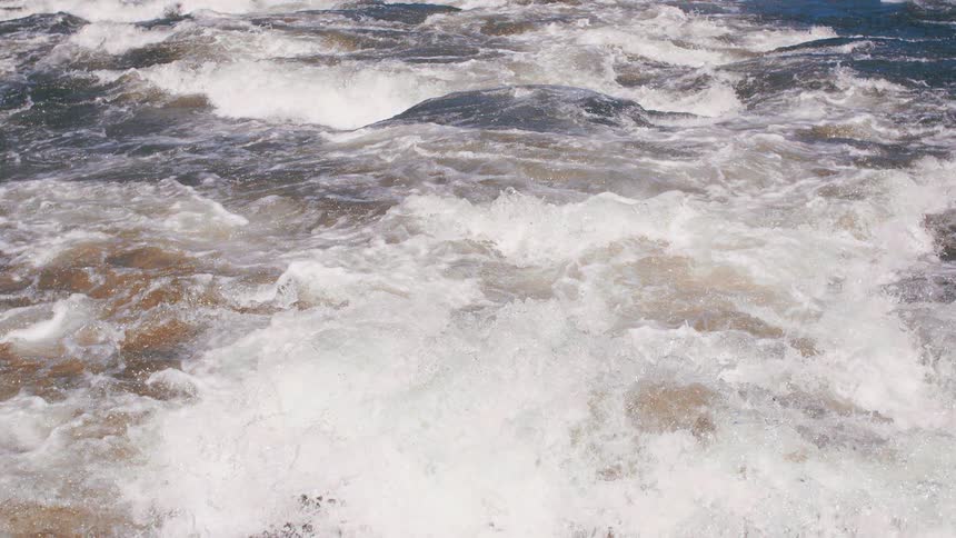 An aerial perspective captures the powerful churning motion of whitewater rapids in a fastflowing river